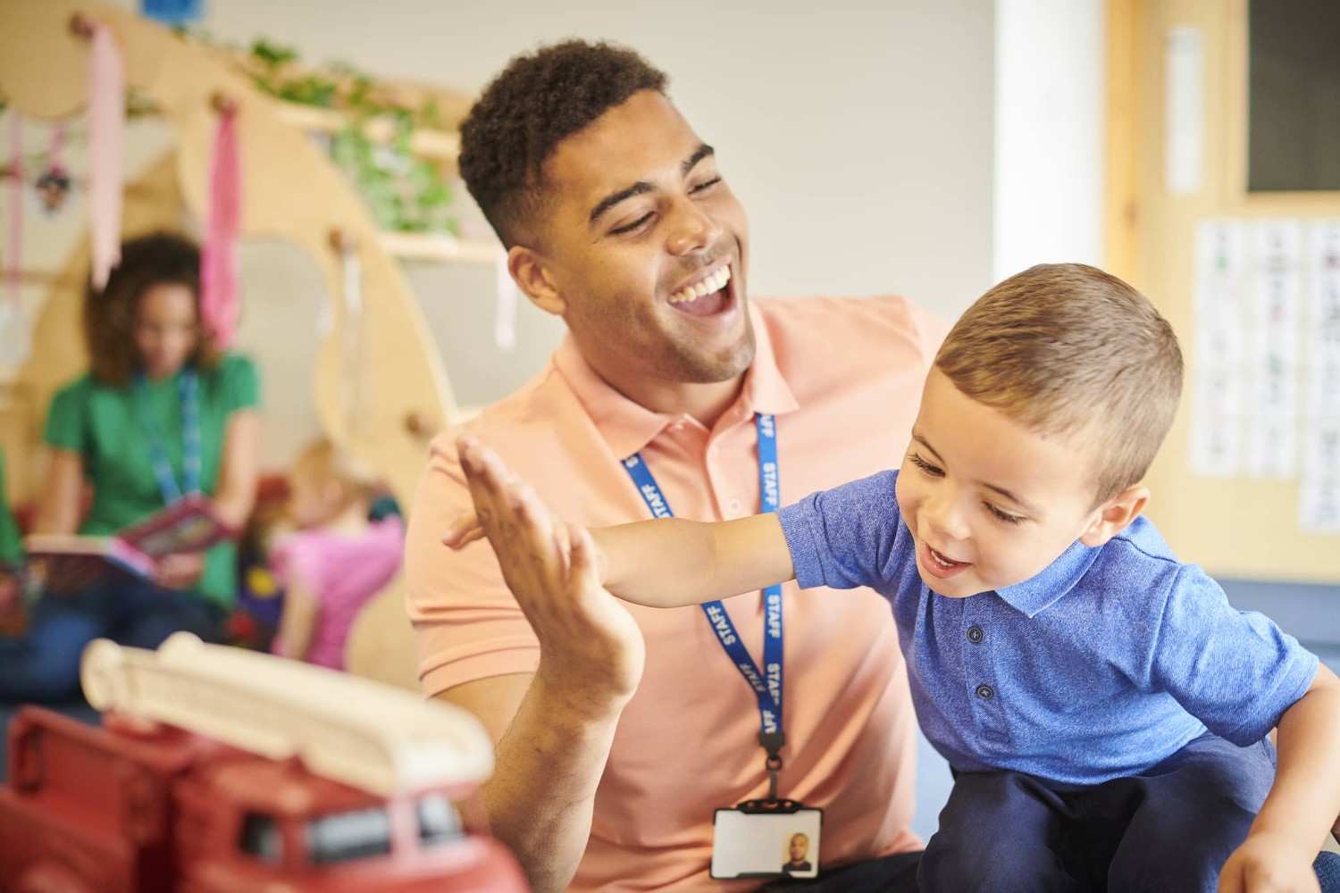 Early childhood educator giving a high five to a young child in a classroom